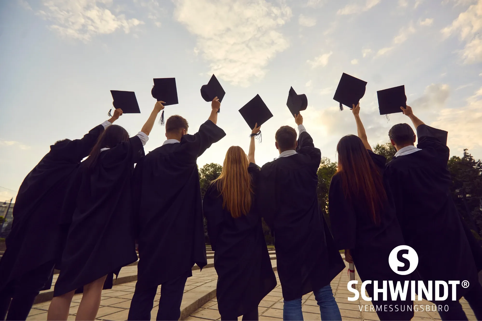 Absolventinnen und Absolventen halten ihre Doktorhüte in die Luft, unten rechts das SCHWINDT-Logo